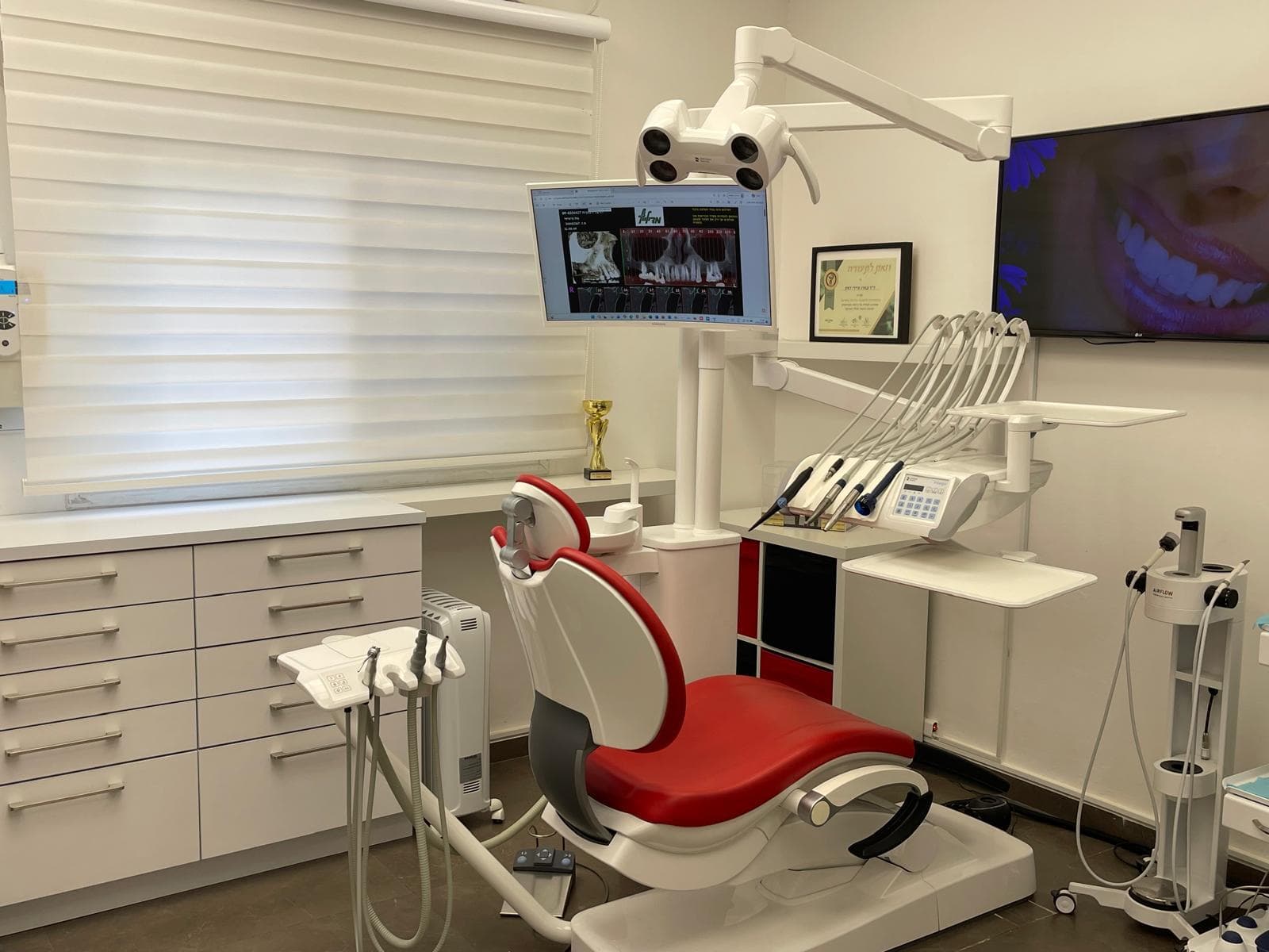 Salle de soins du cabinet à Netanya : fauteuil, scialytique et écran de radiographie